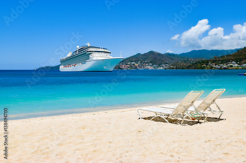 Cruise ship in Caribbean Sea with beach chairs on white sandy beach.
Summer travel concept. photo