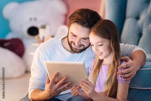 Happy man sitting on blue sofa with daughter