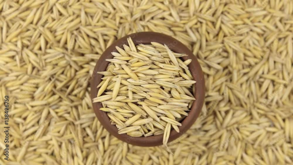 Slow rotation of the grain of oats in a pot made of red clay.
