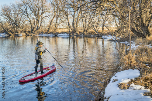Stand up paddler poling on shallow river