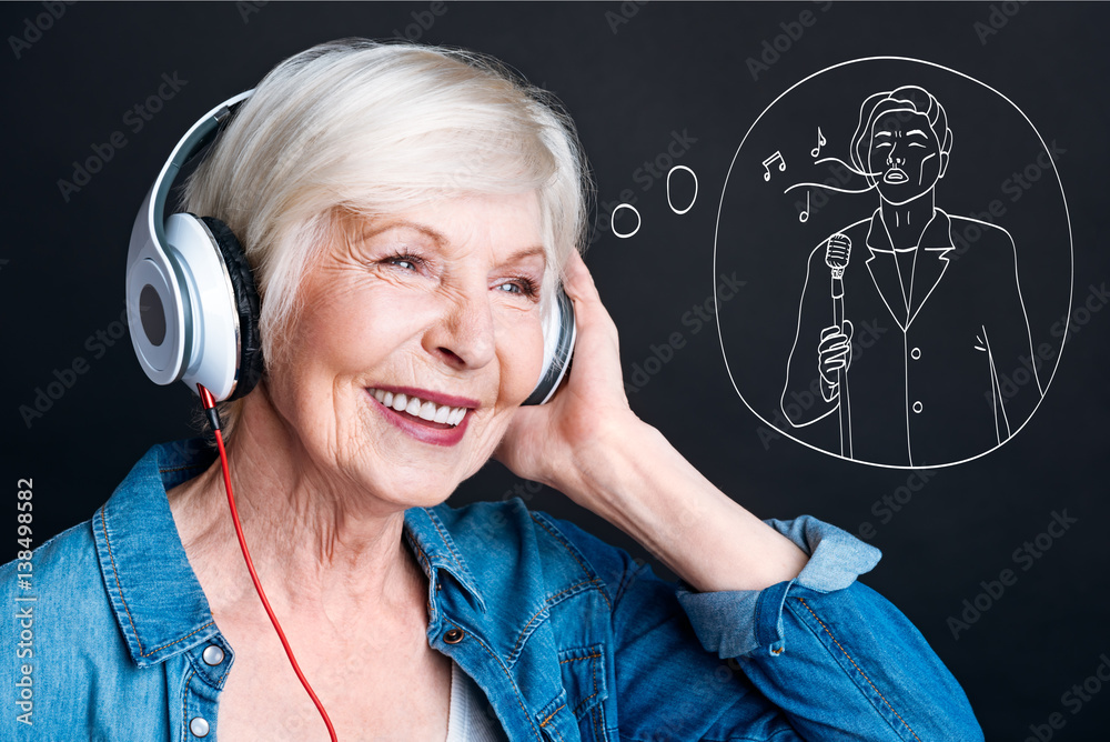 Cheerful aged woman listening to her favourite singer Stock-Foto