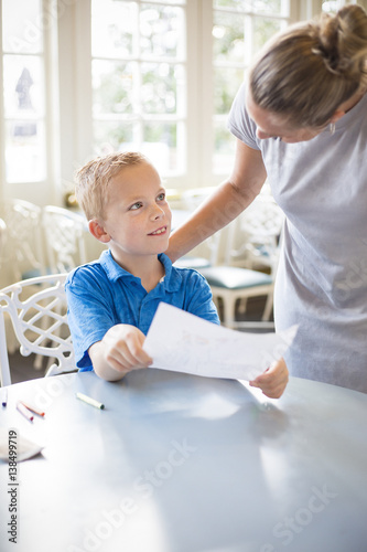 Fotografia cute boy looking up at his female elementary school teacher while seeking approval of his art project