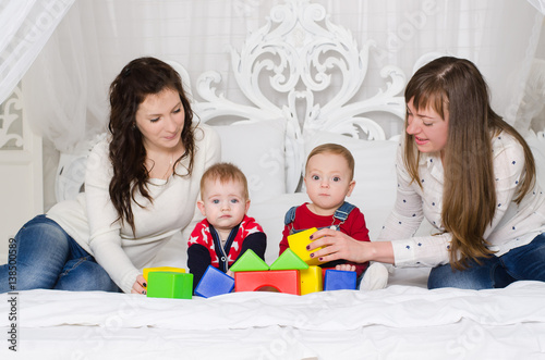 Two mothers with young boys playing with colored cubes