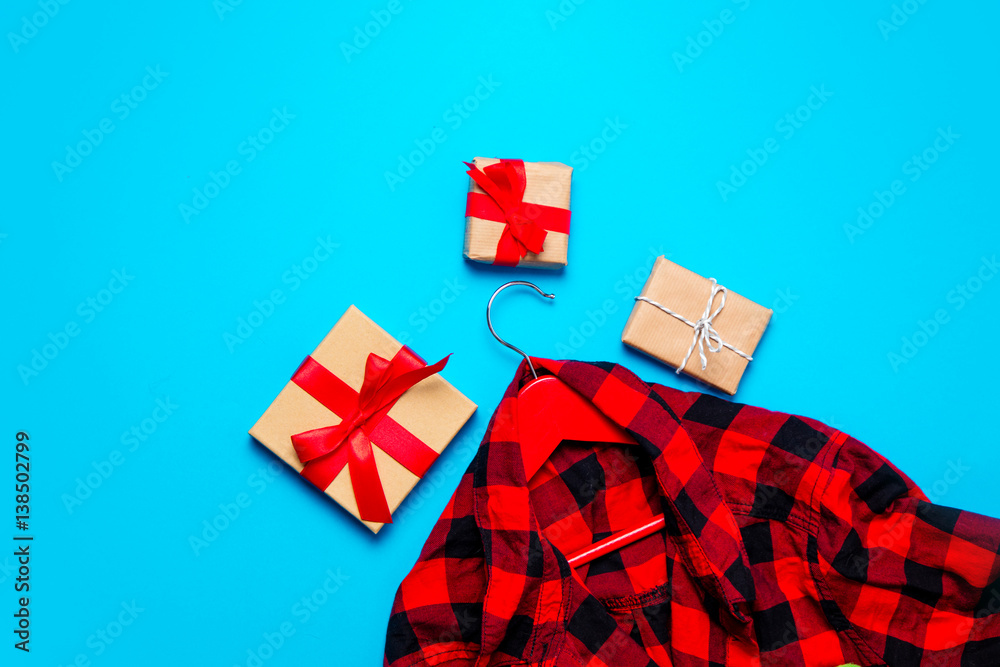 beautiful gifts of different shapes and colors and shirt on hanger lying on the wonderful blue background