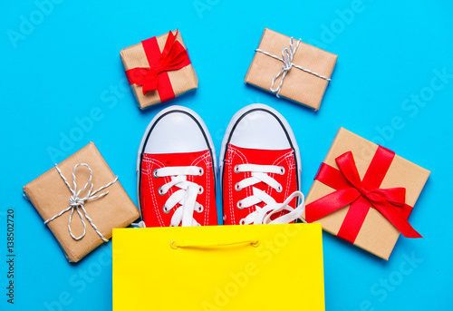 big red gumshoes in cool shopping bag and beautiful gifts on the wonderful blue background photo