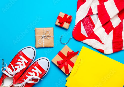 big red gumshoes, cool shopping bag, striped jacket on hanger and beautiful gifts on the wonderful blue background photo