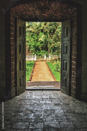 Open doors to the tropical garden, the paved road to the door of the old Indian Villa.Vintage stone floor and walls.