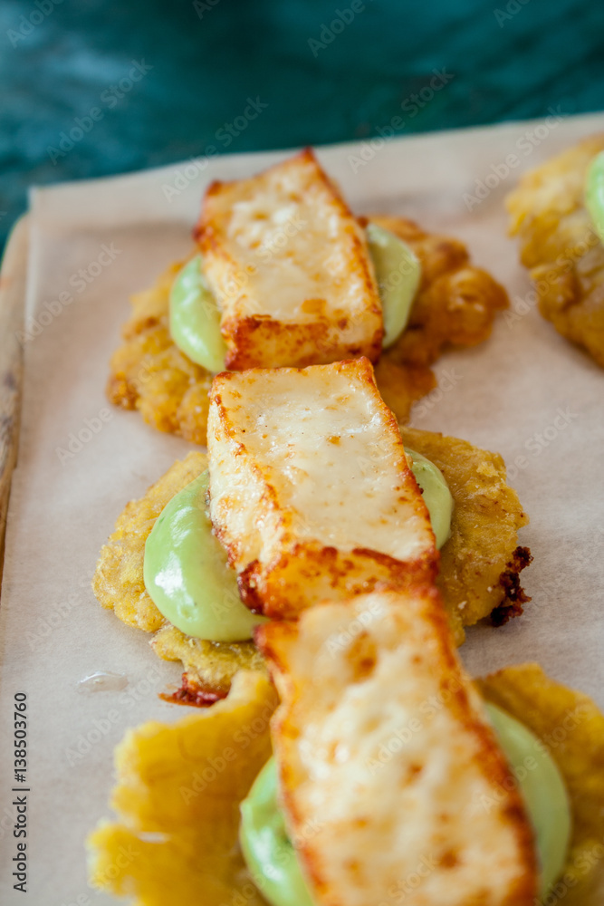 Cheese and avocado tostones, plantain crushed in small portions. In the top a fried cheese. Cheese and avocado tostones, plantain crushed in small portions. In the top a fried cheese.