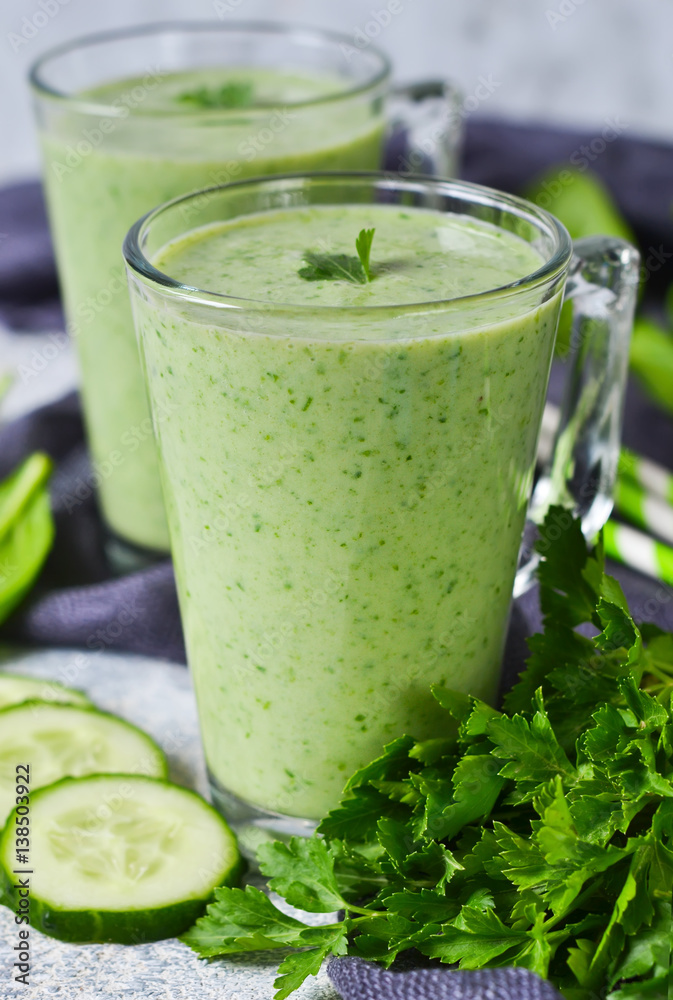 Green vegetable smoothie with avocado, cucumber and spinach on a gray background Green vegetable smoothie with avocado, cucumber and spinach on a gray background