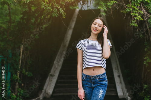 Beautiful girl in stylish jeans and white hat walking in the streets.