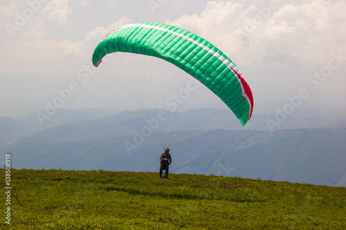 Sporty young man getting ready to fly paraglider