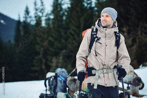 closeup portrait of hiker in sunglasses with backpack against the forest in the Carpathians mountains at winter