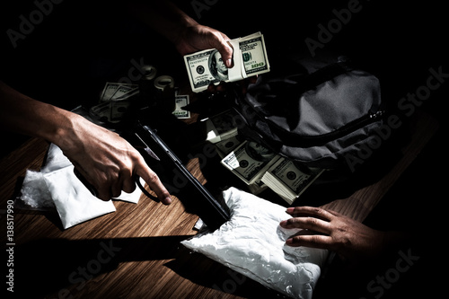Obraz na plátně Drug dealer use gun to push the envelope on the table to buyer