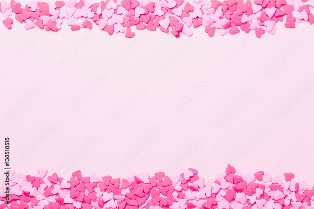 Pink and red heart sprinkles on the pink background. Flat lay, top view.  Valentines background. Romantic border