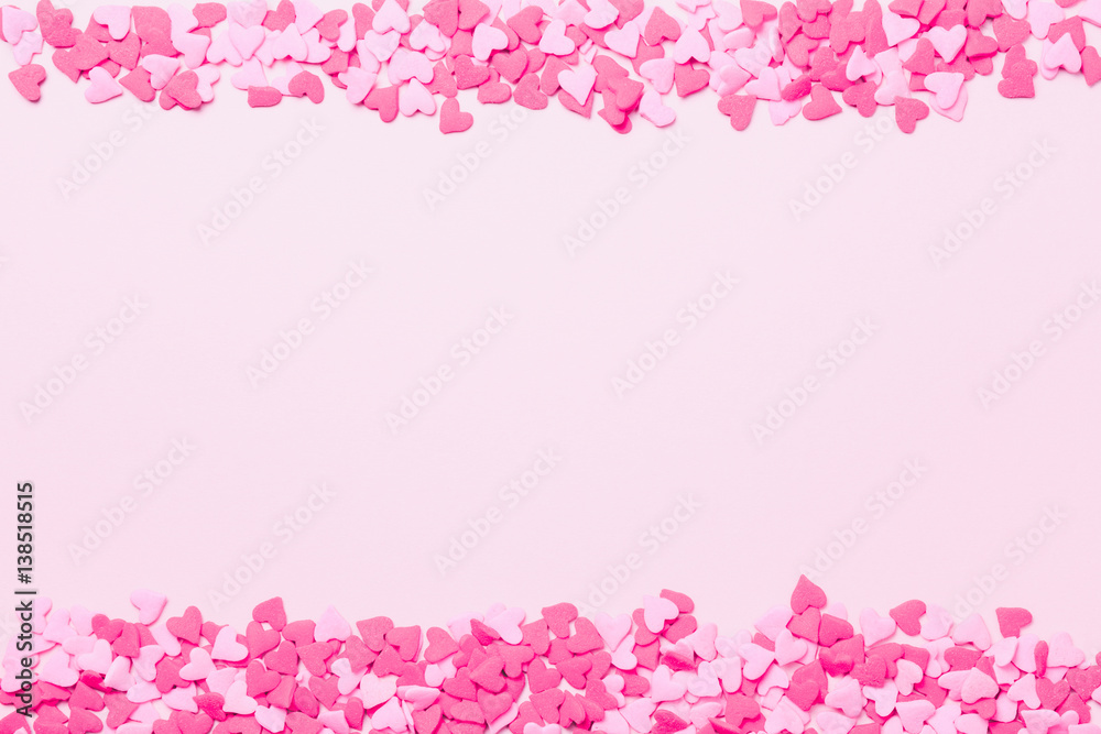 Pink and red heart sprinkles on the pink background. Flat lay, top view. Valentines background. Romantic border Pink and red heart sprinkles on the pink background. Flat lay, top view. Valentines background. Romantic border