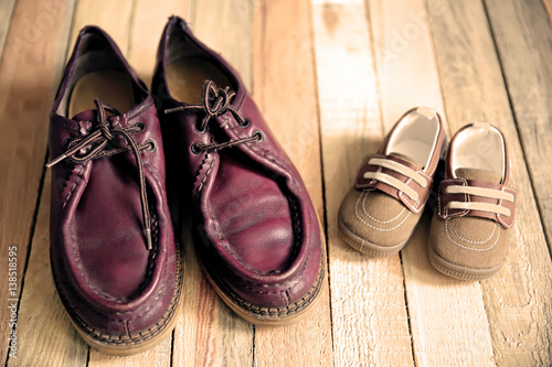 Shoes for father and son on wooden background