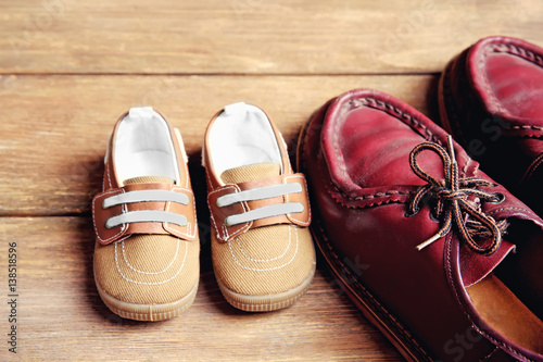 Shoes for father and son on wooden background
