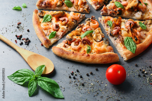 Tasty sliced pizza with seafood and tomato on grey background
