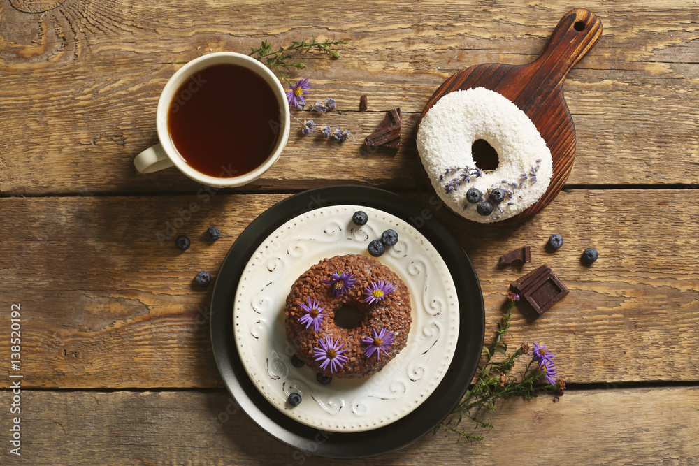 Delicious chocolate doughnuts and cup of coffee on wooden table Delicious chocolate doughnuts and cup of coffee on wooden table