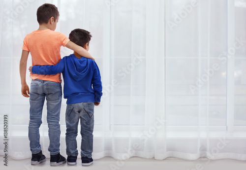 Papier peint Little brothers standing together near window at home