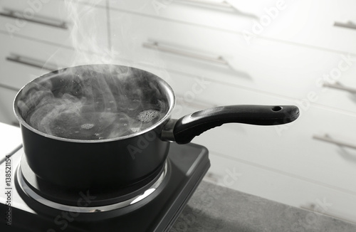 Metal saucepan on electric stove in kitchen