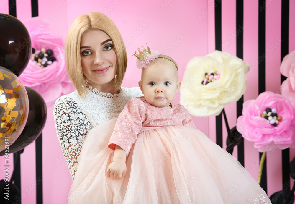 Mother with cute baby girl in room decorated for birthday party