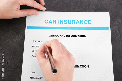 Hand filling in car insurance form, closeup