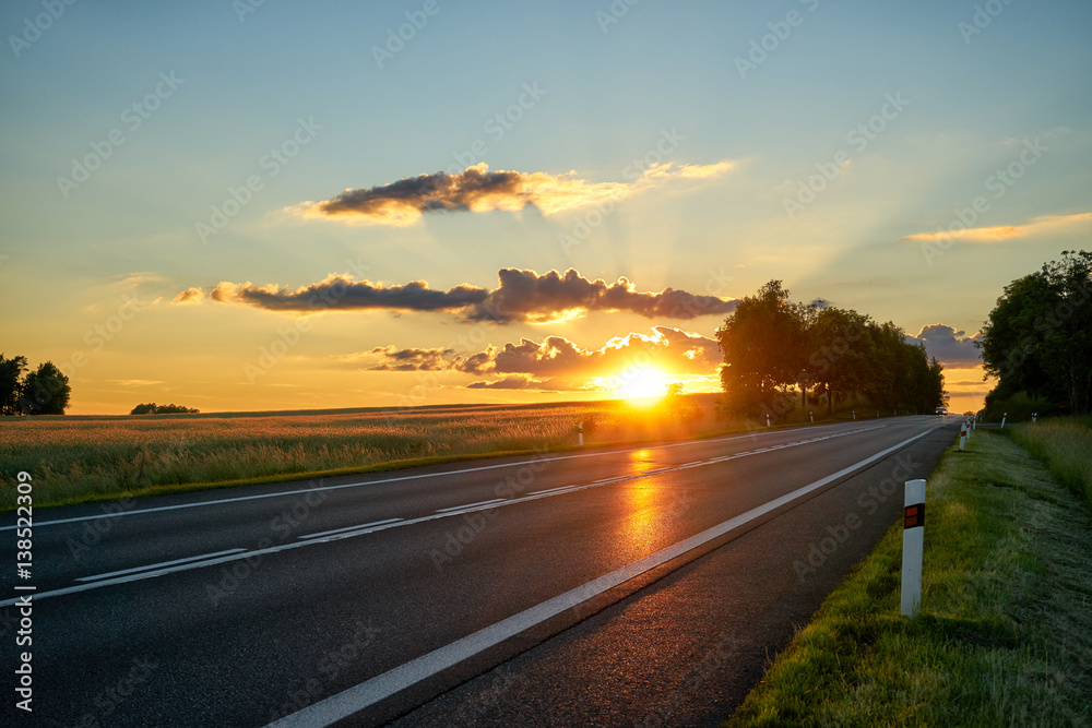 Sunset over the empty asphalt road in a rural landscape