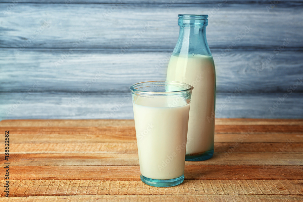 Glass of tasty milk with bottle on wooden table Glass of tasty milk with bottle on wooden table