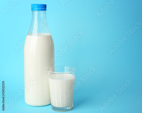 Bottle of tasty milk with glass on blue background