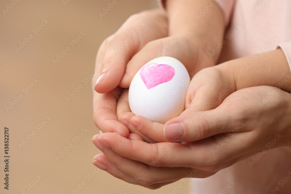 Hands of little child and mother holding Easter egg, closeup Hands of little child and mother holding Easter egg, closeup