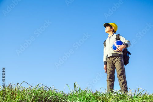 サッカーボールを持ち遠くを見つめる小学生の男の子