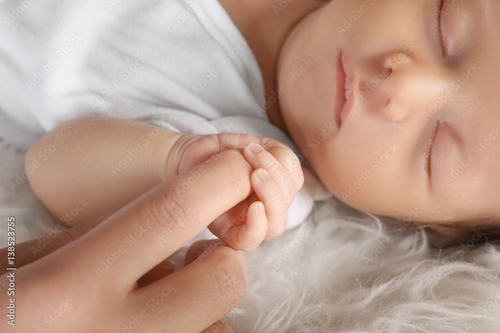 Cute little baby holding mother's finger while sleeping, closeup Cute little baby holding mother's finger while sleeping, closeup