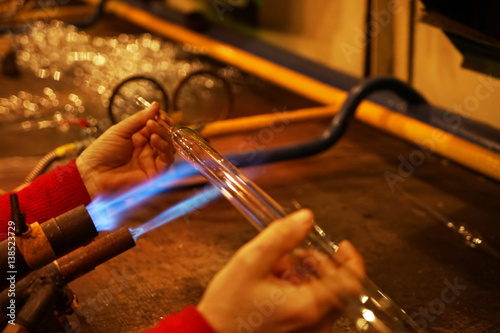 Glassblower heating glass for shaping Christmas ornament