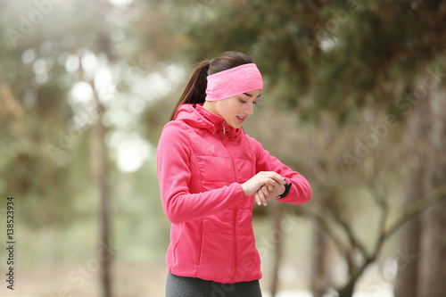 Young woman with fitness tracker on winter park background