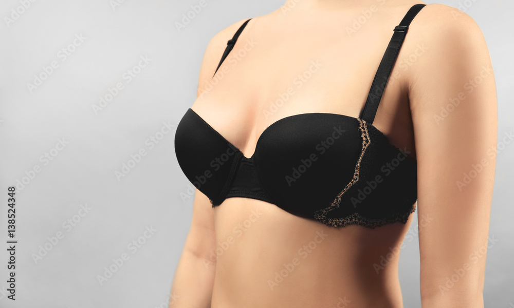 Young woman in black bra on light background, closeup Young woman in black bra on light background, closeup
