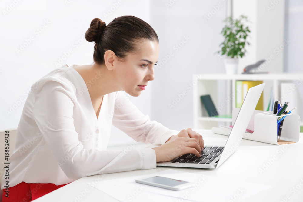 Incorrect posture concept. Young woman sitting at table in modern room - obrazy, fototapety, plakaty 