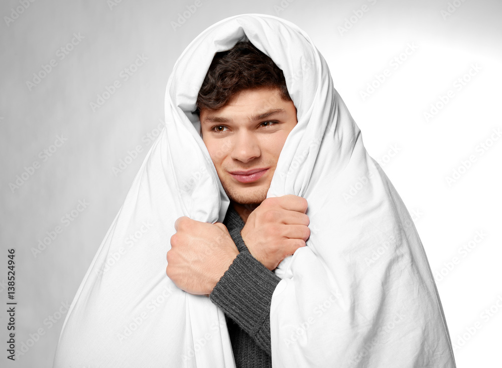 Young ill man wrapped in blanket on white background Young ill man wrapped in blanket on white background