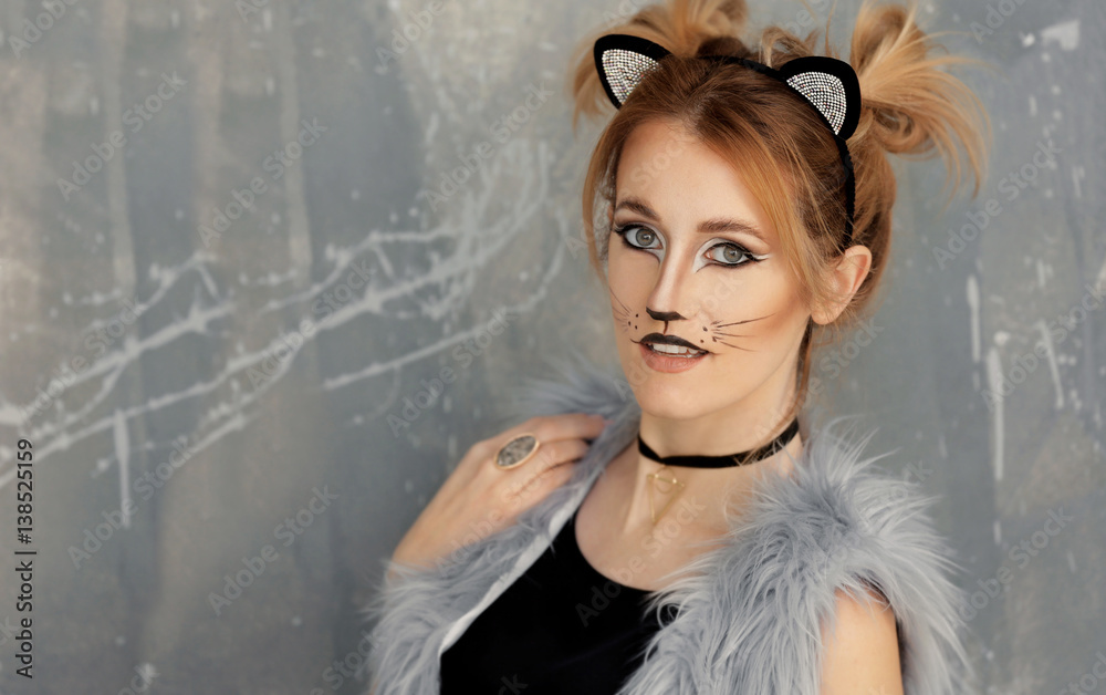 Beautiful young woman with cat makeup and ears on grunge background