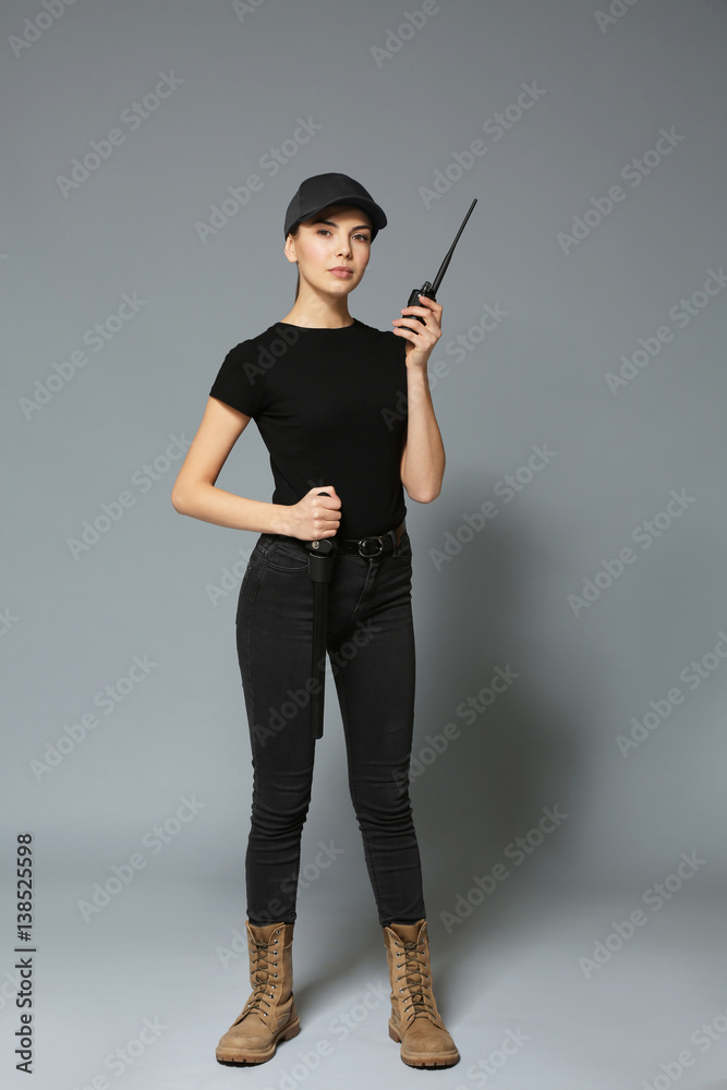 Beautiful young woman in security uniform on grey background Beautiful young woman in security uniform on grey background