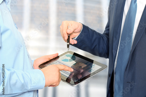 Business colleagues working and analyzing financial figures on a digital tablet