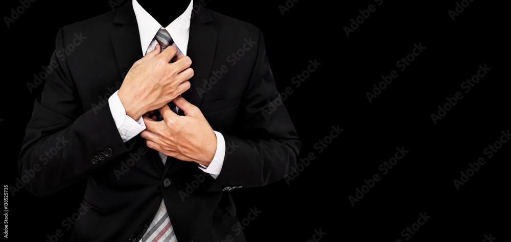 Businessman touching necktie, isolated on black background with copy space
