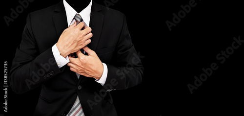 Businessman touching necktie, isolated on black background with copy space