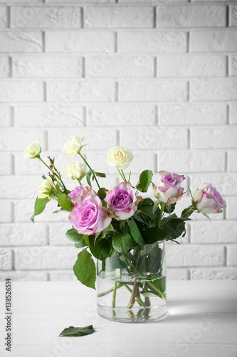 Fototapeta Naklejka Na Ścianę i Meble -  Glass vase with bouquet of beautiful flowers on brick wall background