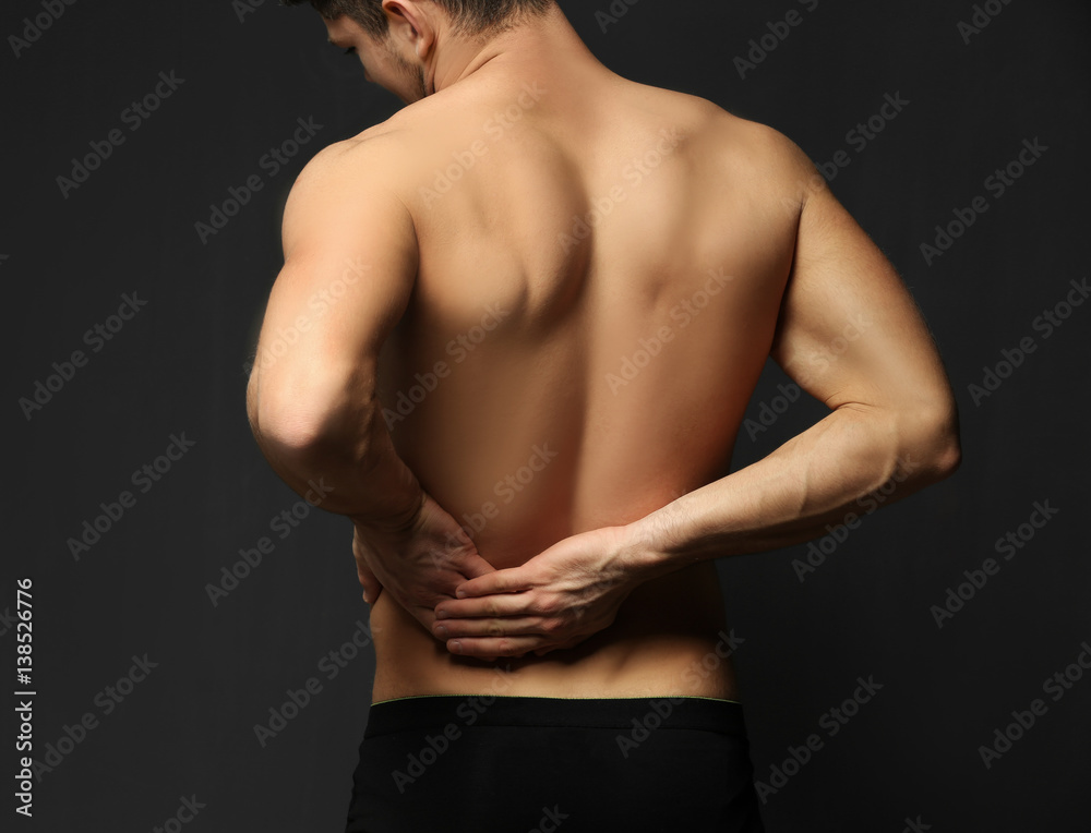Naklejka premium Young man suffering from backache on dark background