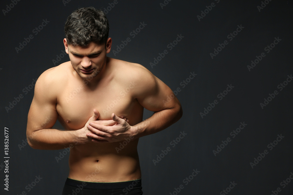 Handsome man having heart attack on dark background Handsome man having heart attack on dark background
