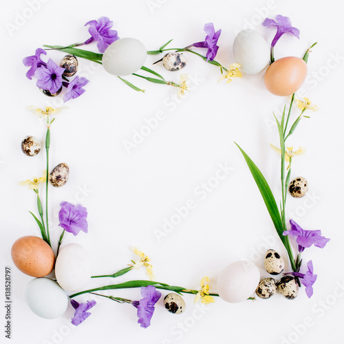 Frame wreath made of Easter eggs, quail eggs, yellow and purple flowers on white background. Flat lay, top view. Traditional spring concept. Easter concept.