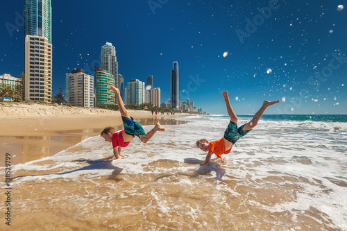 Two happy boys doing hand stands on Gold Coast beach, Australia