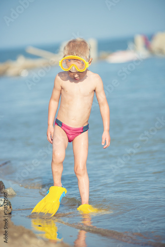 Little boy with snorkel by the sea. Cute little kid wearing mask and flippers for diving at sand tropical beach. Ocean coast.
