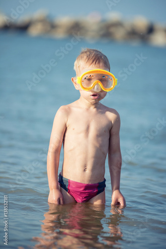 Little boy with snorkel by the sea. Cute little kid wearing mask and flippers for diving at sand tropical beach. Ocean coast.
